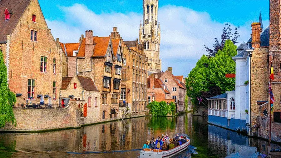 Small group of people in a boat floating down a Dutch waterway with brick buildings lining each bank