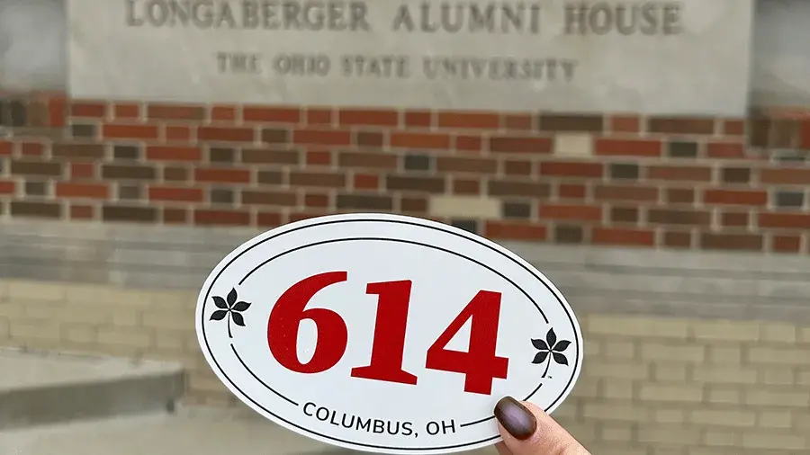 614 sticker being held up in front of the Longaberger Alumni House