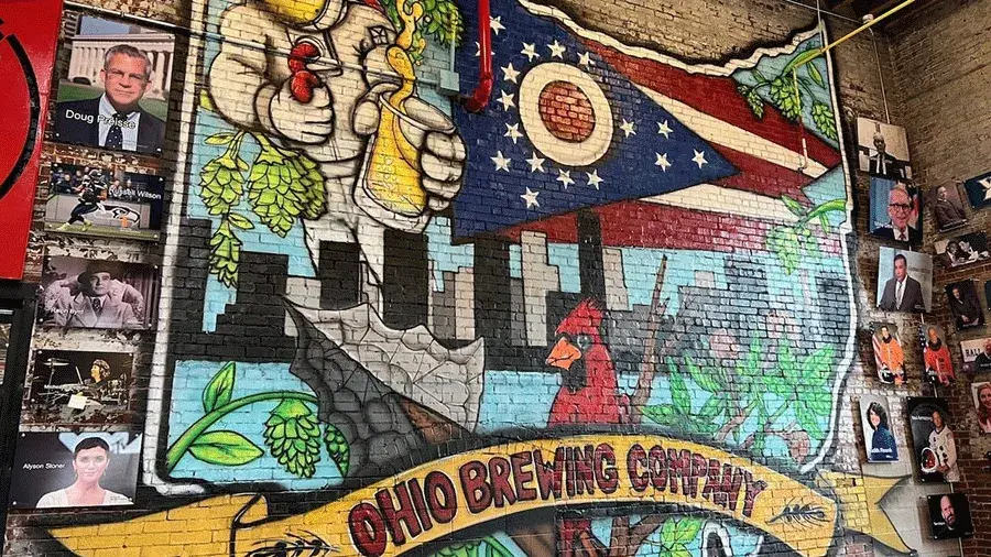 a painted brick wall with a collage of artwork inside the shape of Ohio and text reading Ohio Brewing Company