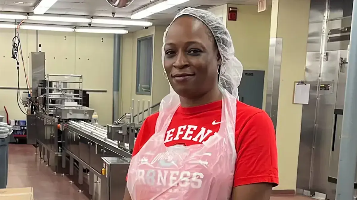 woman wearing an ohio state t-shirt packing meals in a kitchen