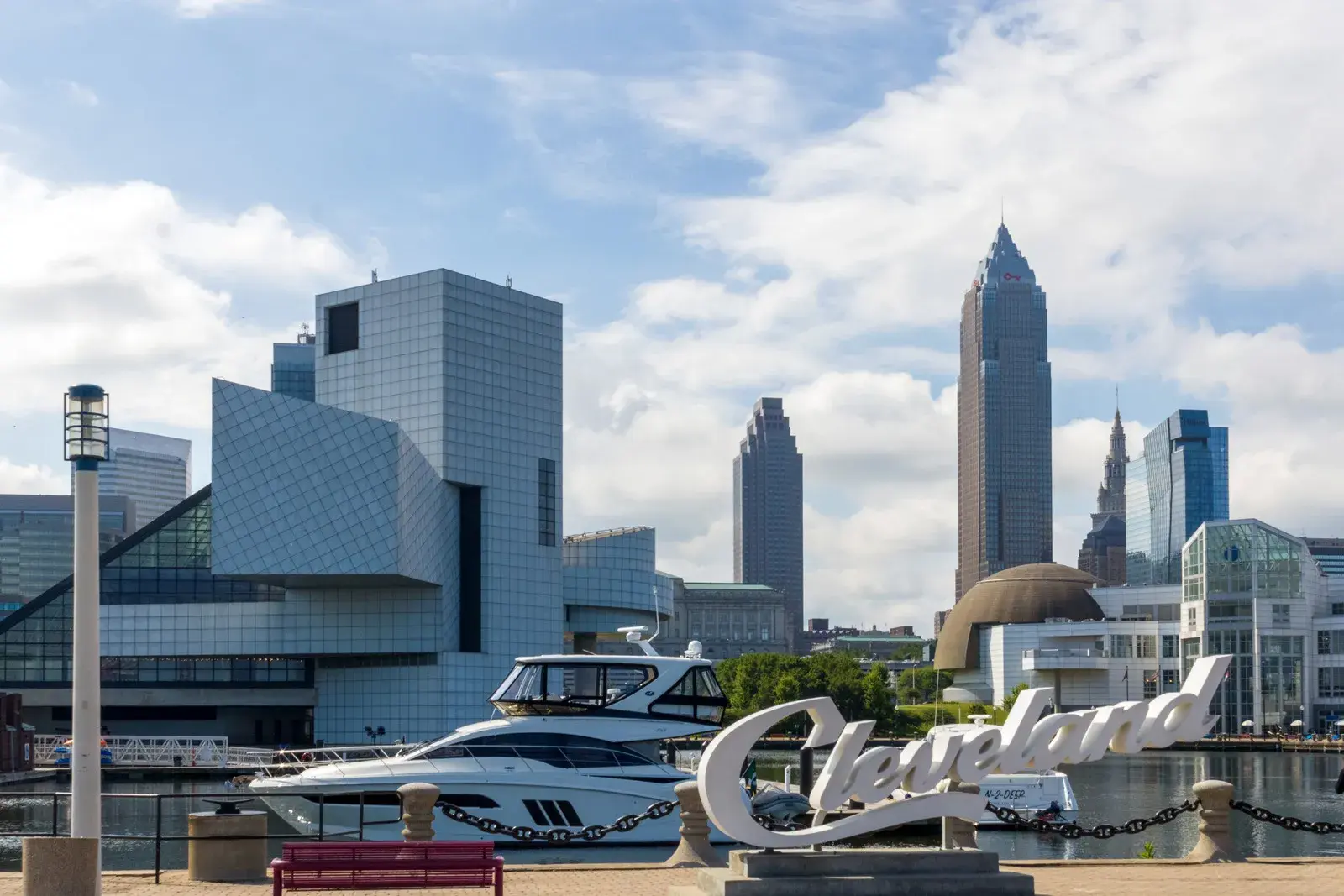 A view of the waterfront with modern buildings, a boat and a Cleveland sign