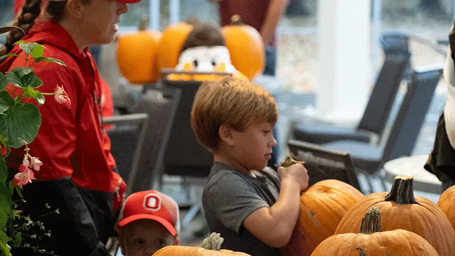 a child picking up a pumpkin
