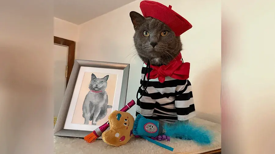 A cat dressed up as a French painter next to a painting of a cat