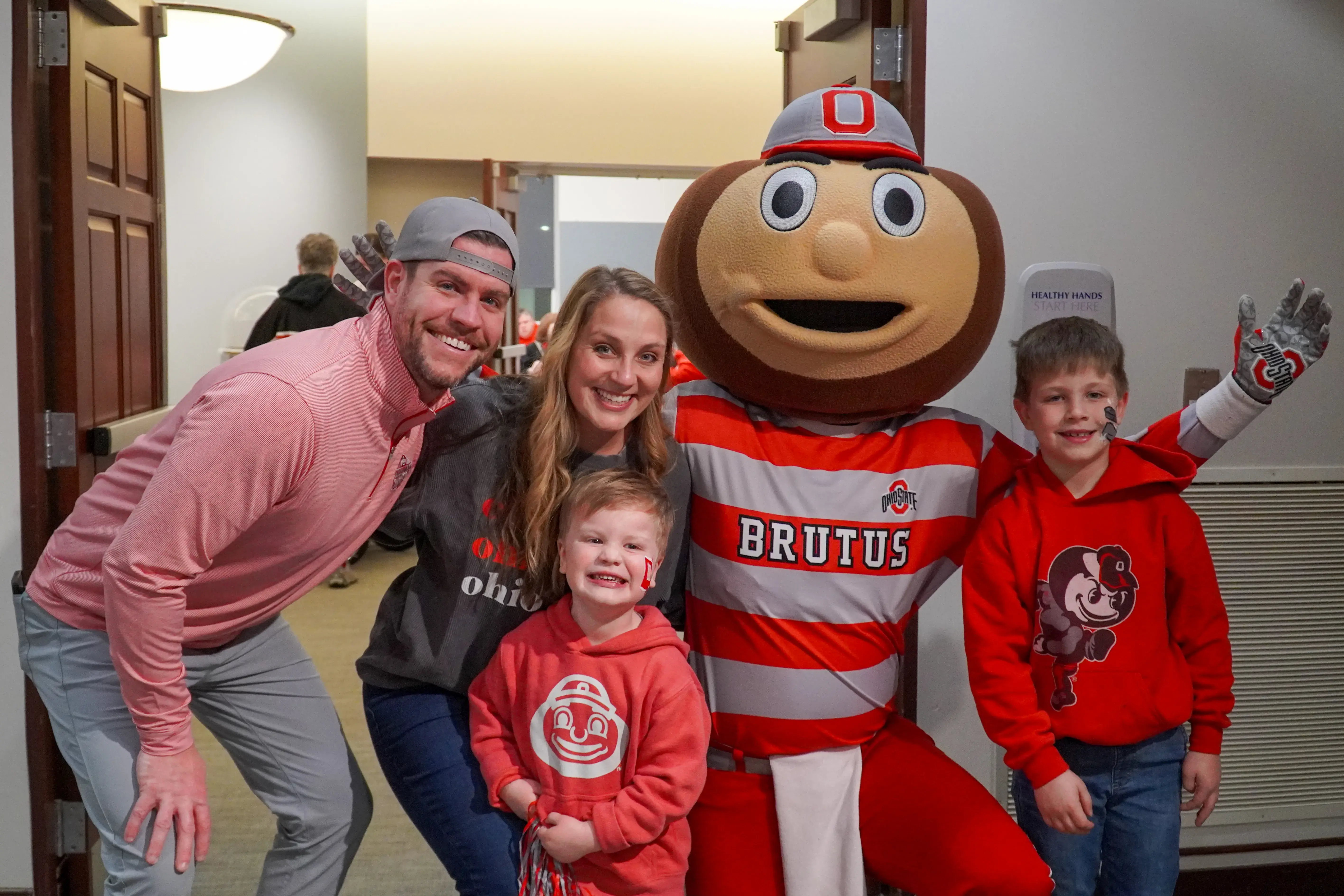 Two parents and their two kids smiling in a photo with the Brutus mascot