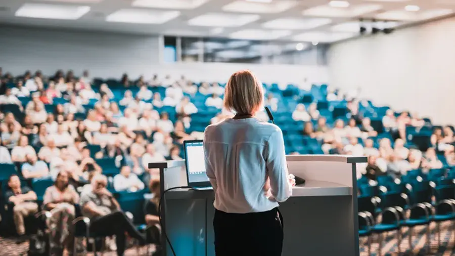 Female presenter in front of a lecture hall.