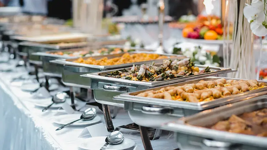 Various types of food in metal pans on catering tables.