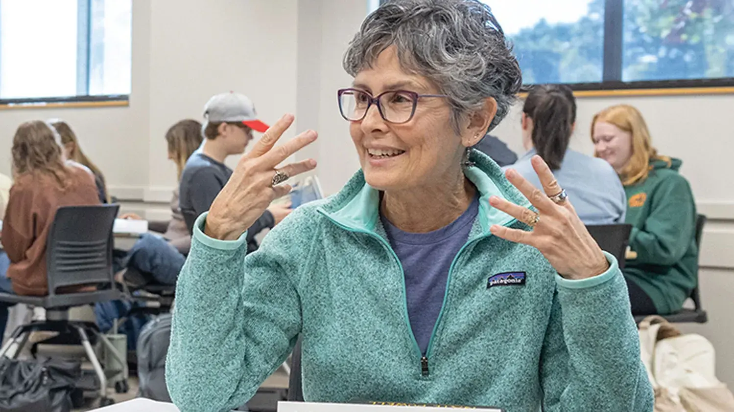 An older woman with short gray hair gestures as she makes a point during a small group discussion inside an Ohio State classroom.