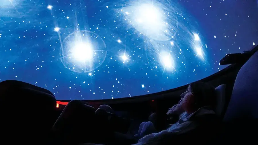 A group of people sitting in a planetarium