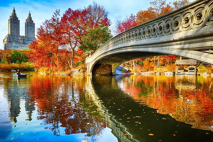 A bridge reflecting over a waterway surrounded by fall-colored trees
