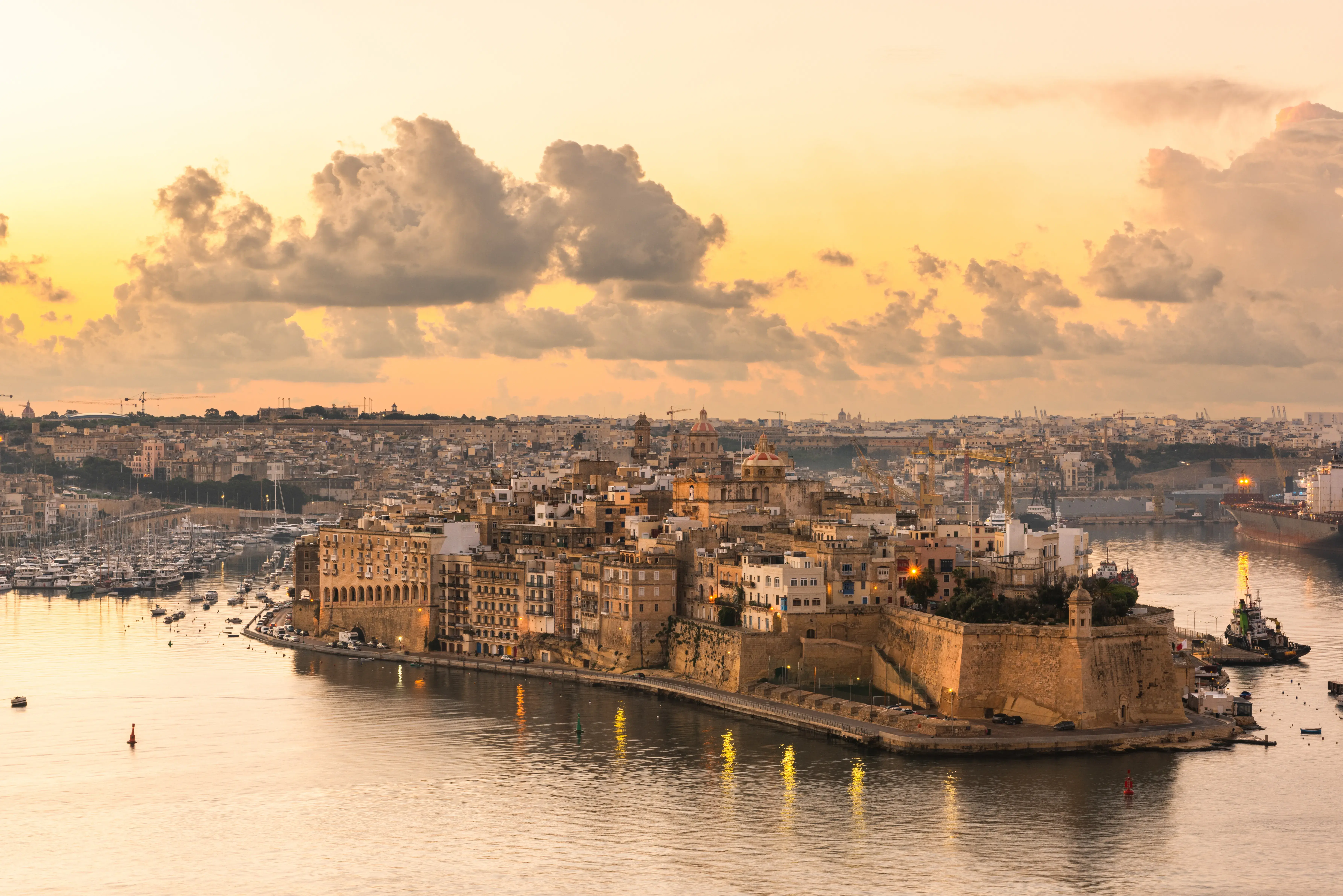 Sunset view of the Three Cities waterfront across Grand Harbour, Malta.