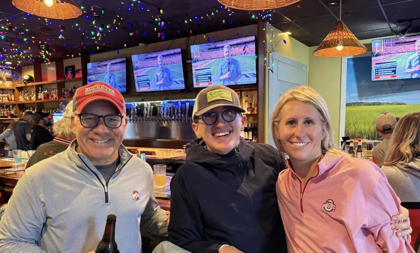 Two women and a man smiling at a Charleston alumni social event.