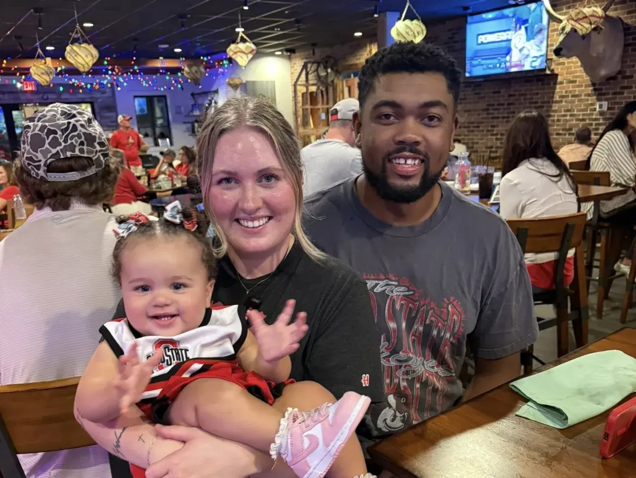 Charleston alumni couple with their baby at a social event.