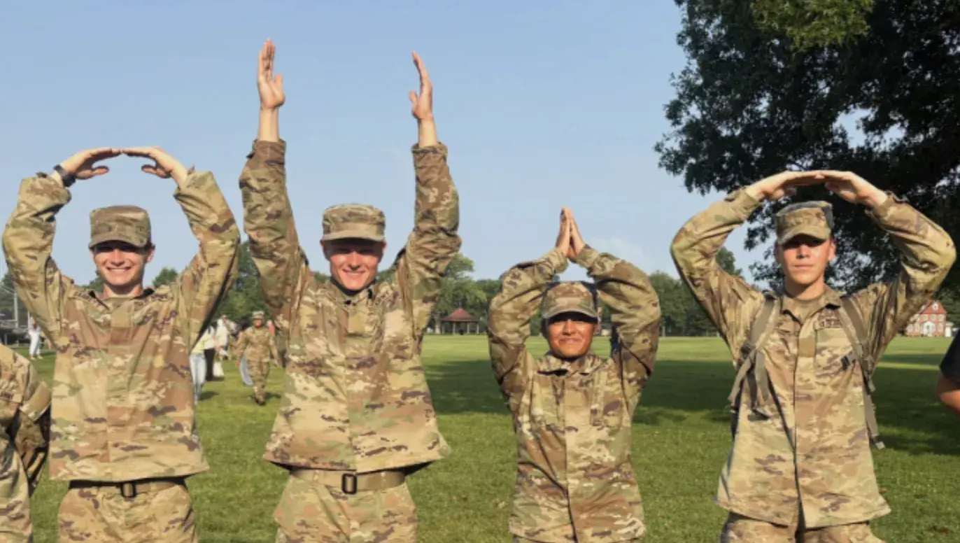 Army rotc members doing the O-H-I-O sign with their arms.