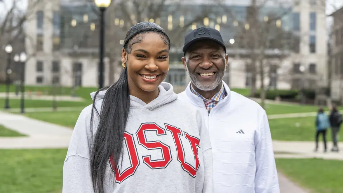 Faith and Keith Hunter smile as they pose on the Oval in front of Thompson Library.