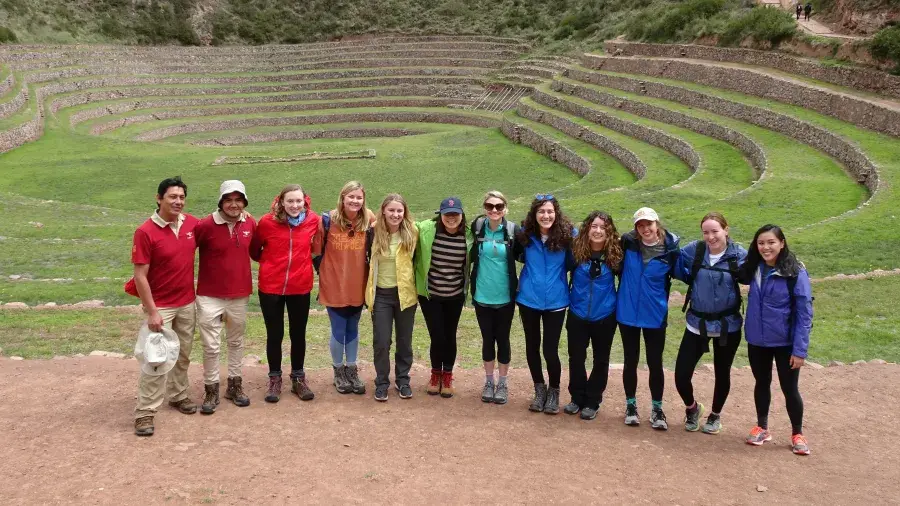 Group of 11 people standing together in front of large green agricultural terraces built into a hillside.