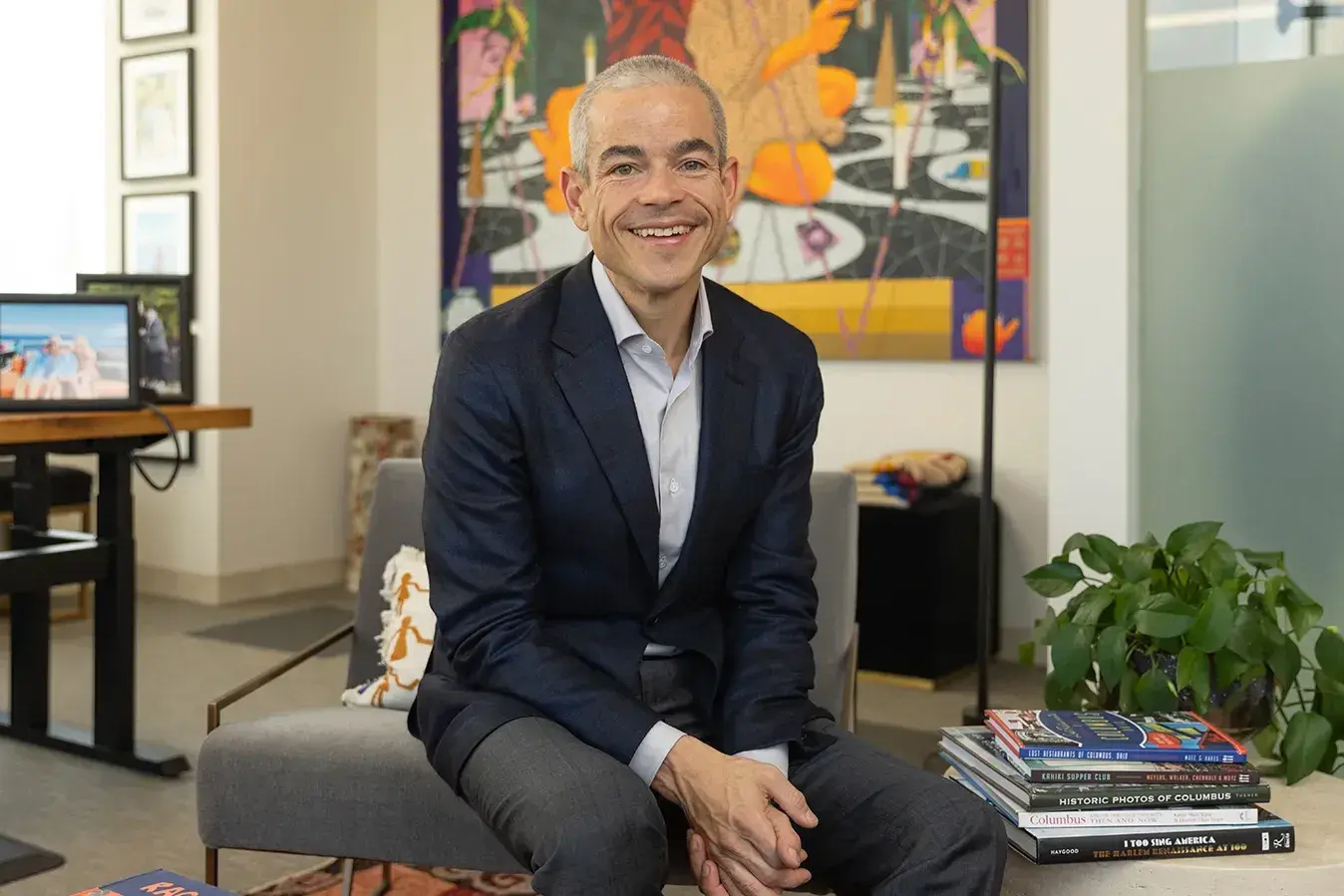 Matt Scantland smiles as he poses for a portrait in his office. He's a thin, white, middle age man with close cropped hair wearing a sportcoat. His smile is genuine.