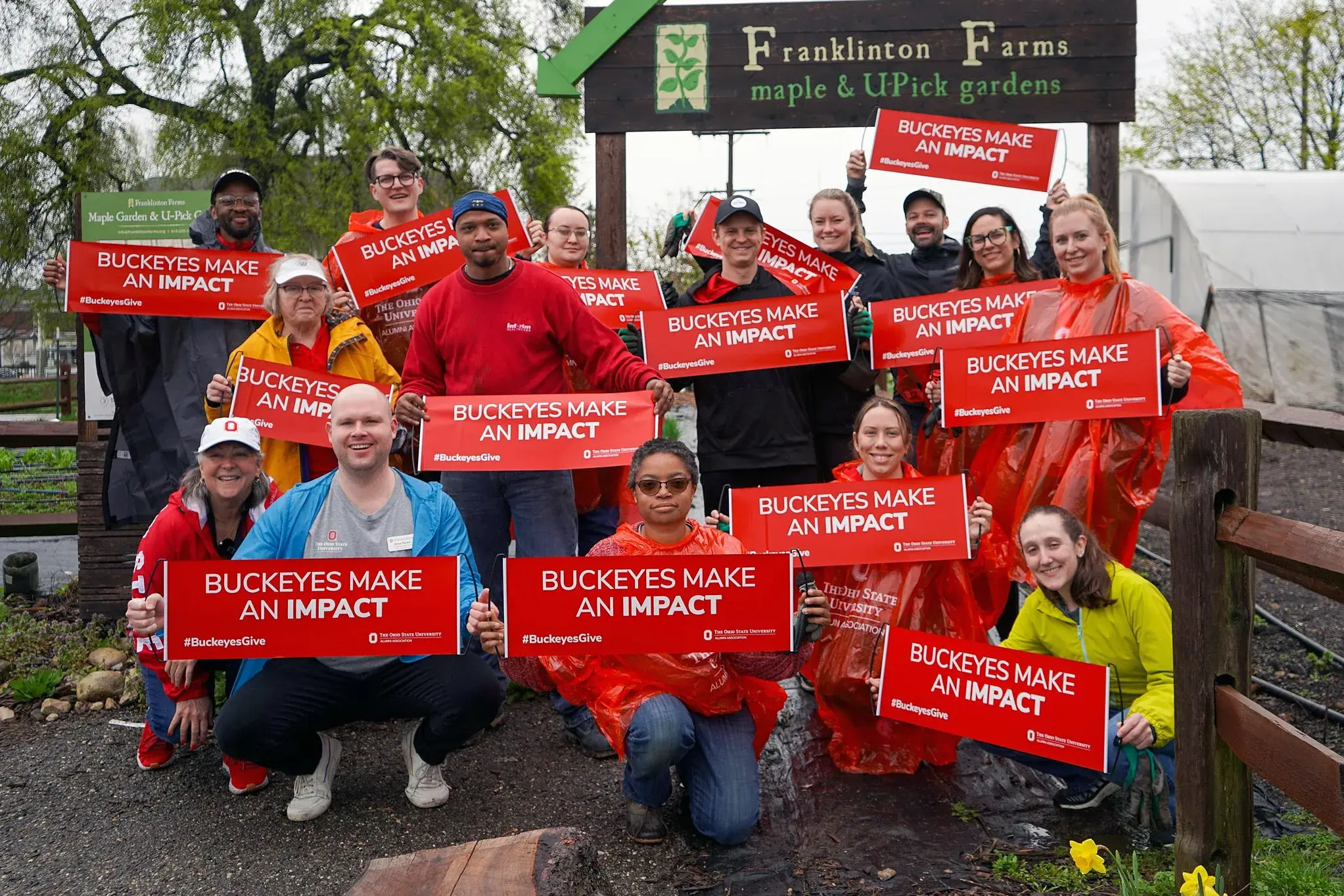 dozen of buckeye volunteers holding red signs that say buckeyes make an impact