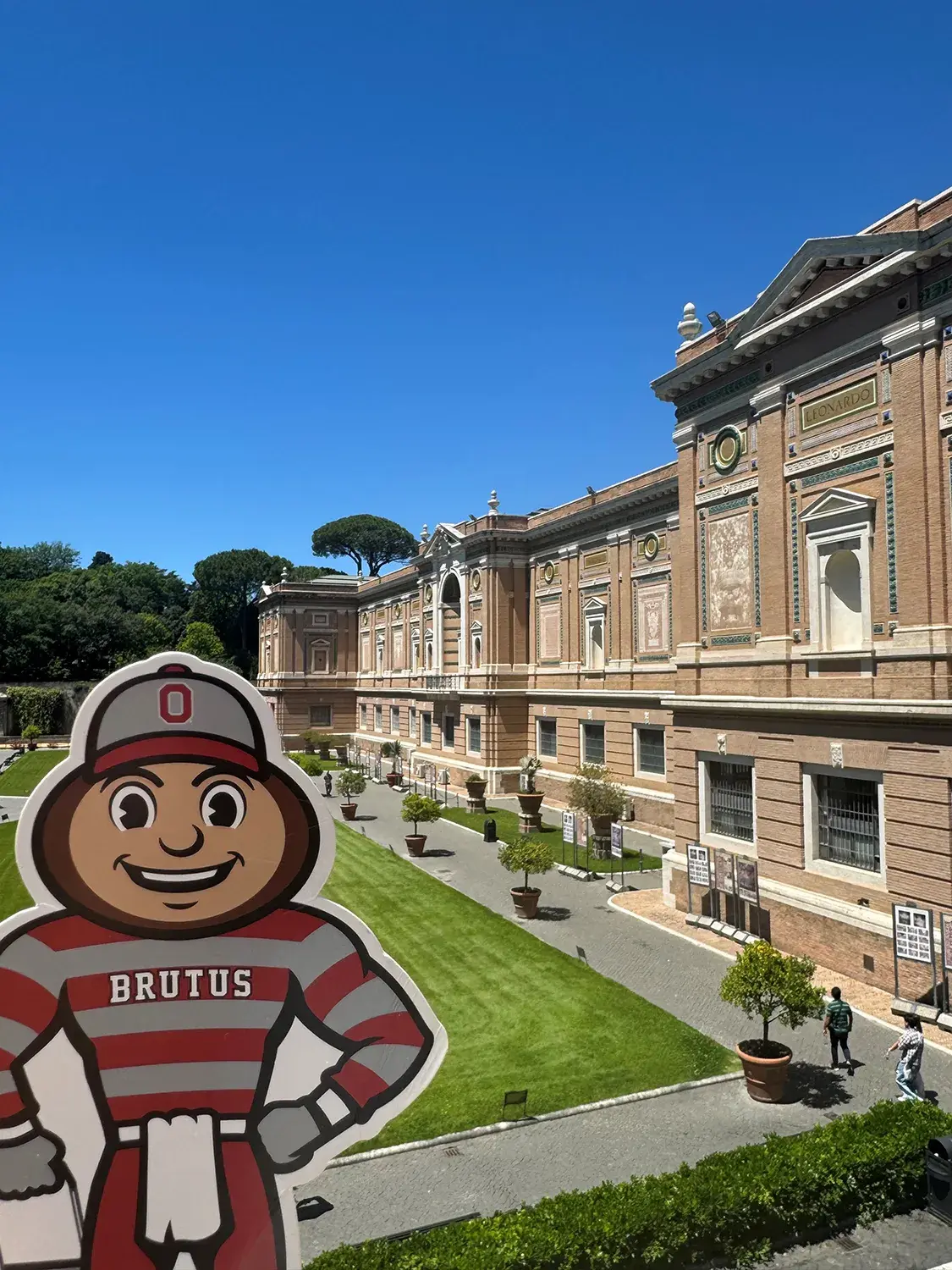 Brutus in front of a well-trimmed yard and the Vatican Pinacoteca in Vatican City.