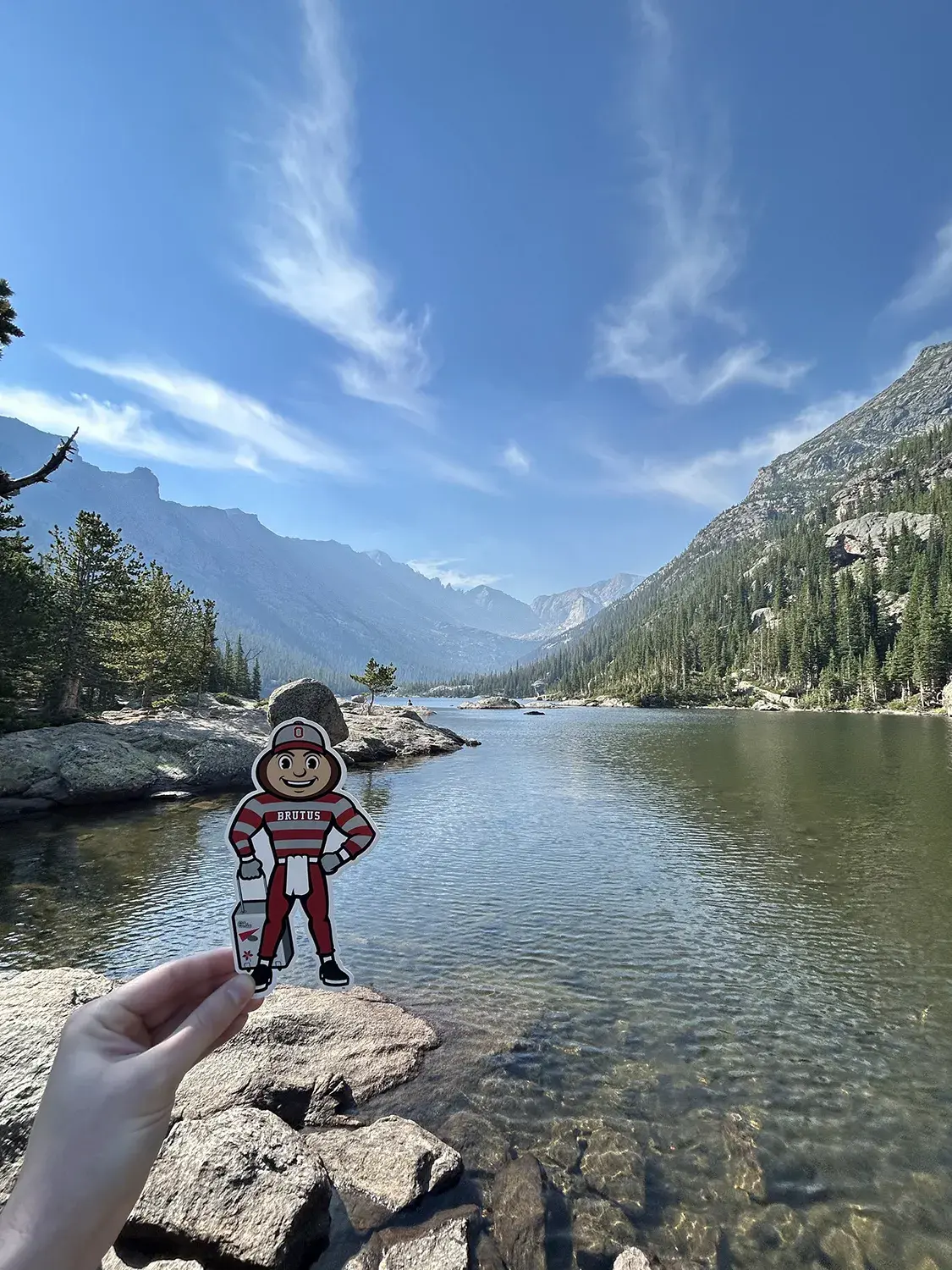 Brutus by a calm river winding between mountains in Estes Park, Colorado.