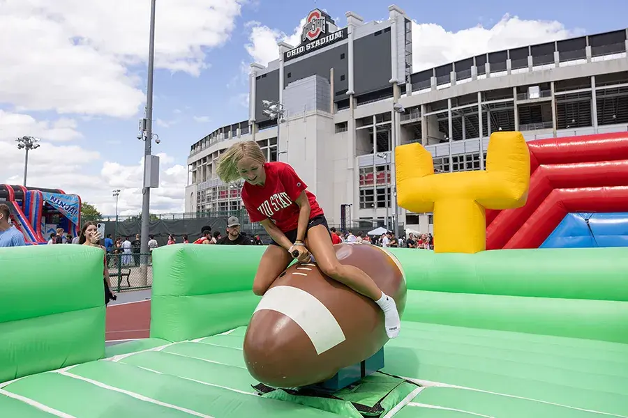 During welcome week, a first-year student rides a giant football like a bucking bronco.