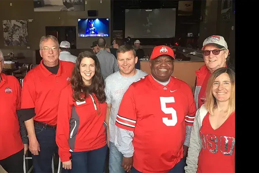 Group of people in the Ohio State clothing posing together in a restaurant.