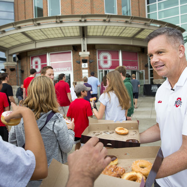Buckeyes basketball coach Chris Holtmann offers a sweet hello to incoming students and families. “They’re probably a little anxious and nervous. Maybe it’ll help them if they see a smiling face,” he says. “And who doesn’t like donuts in the morning? Donuts can wipe away tears.”