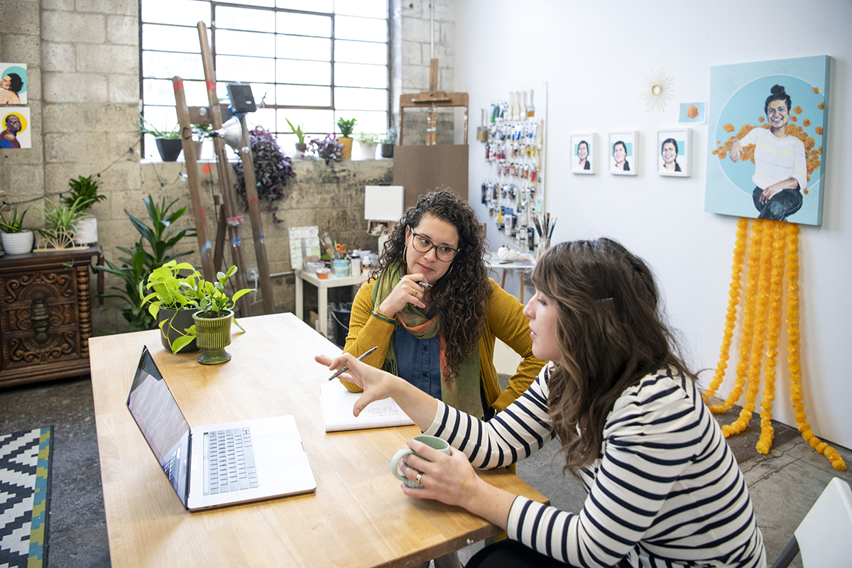 Mary Rodriguez works with a colleague who is gesturing to a laptop computer