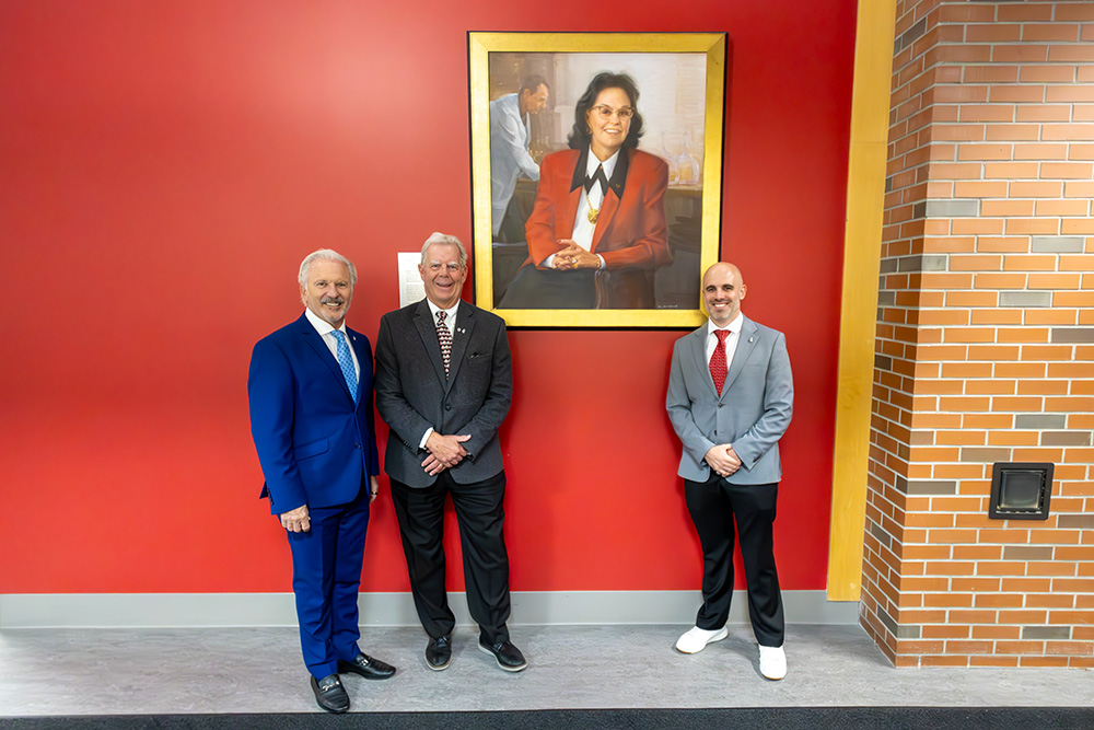 Three men standing by a portrait of a woman