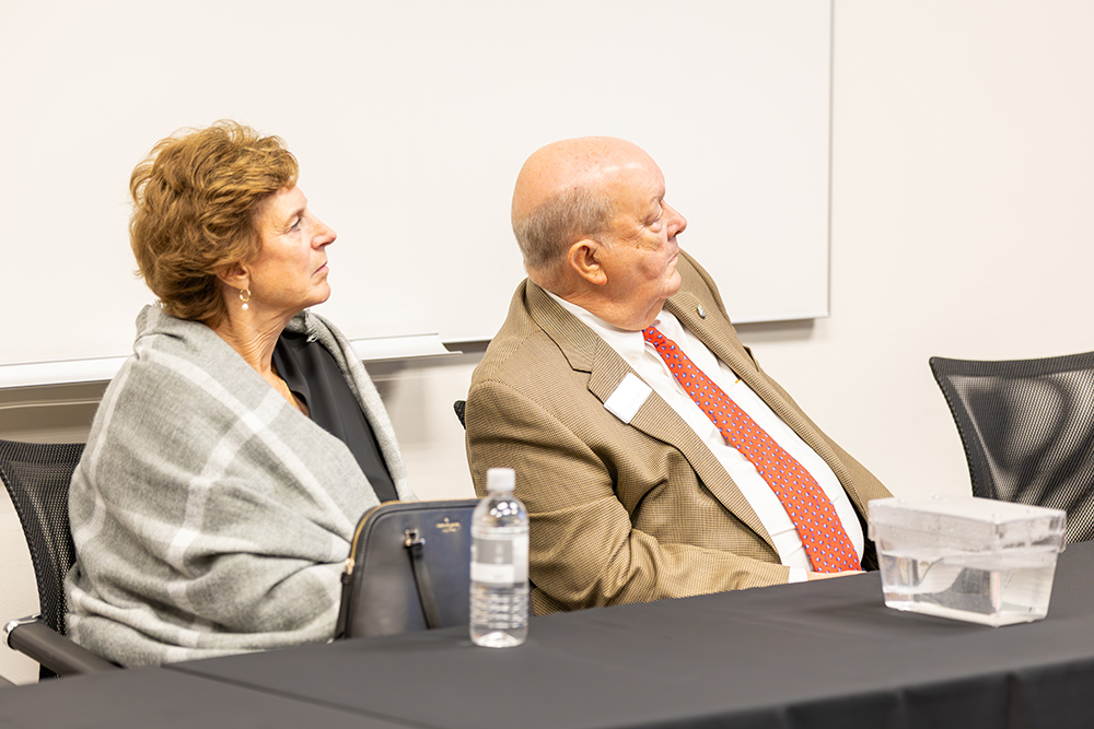 A man and woman sitting down looking a presenter