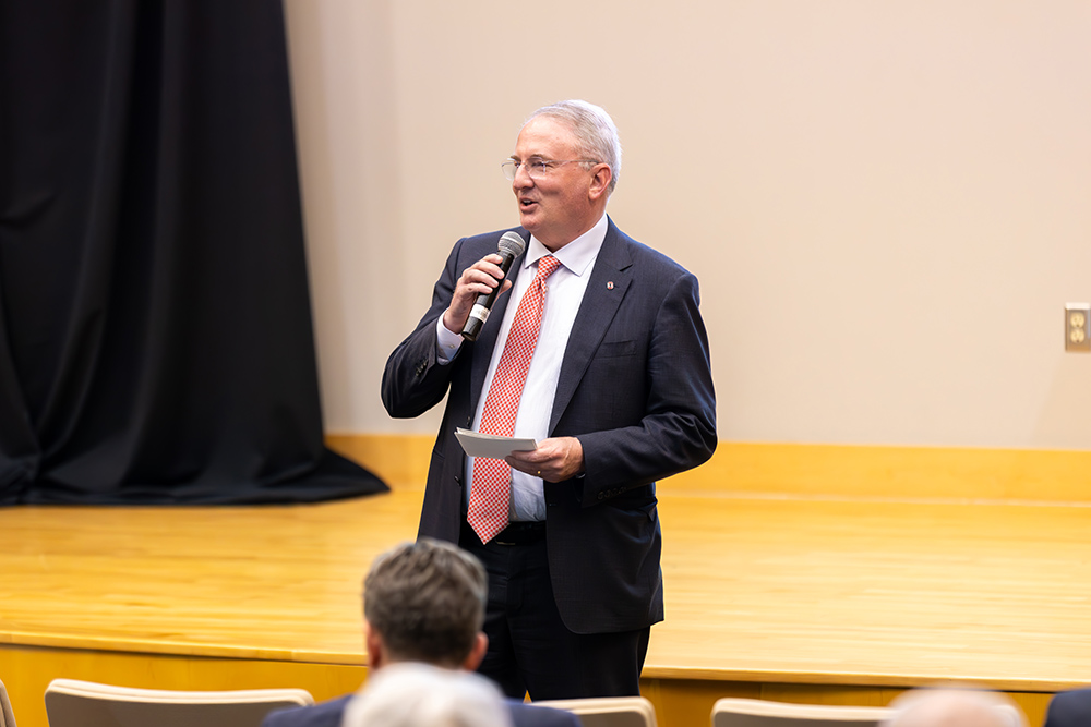 A man in a suit talking with a microphone in his hand