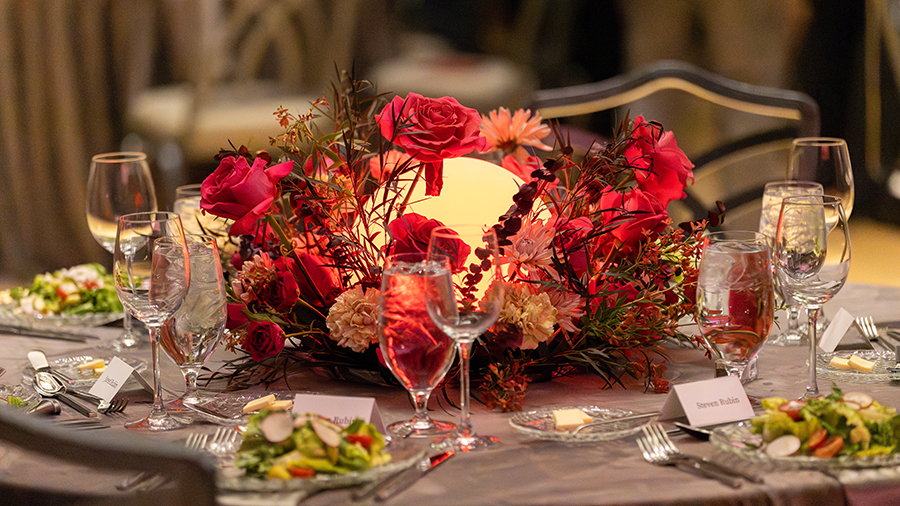 Table setting at an event with pink and red florals.