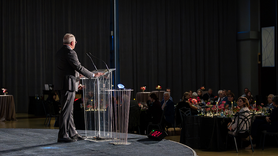 Presenter at a glass podium addressing the audience.