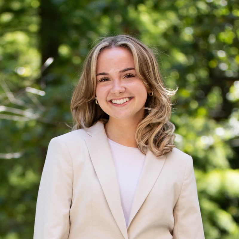 Ally Lewis headshot with greenery in background.