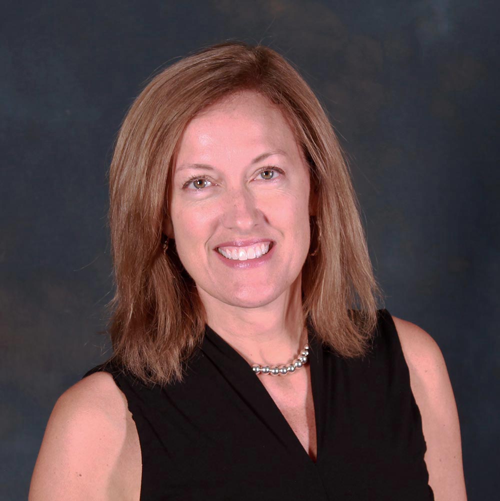 Lynne Deshler wearing a sleeveless black top and shiny pearl necklace