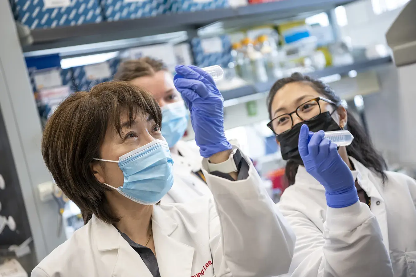 medical professionals hold up test tubes to examine them