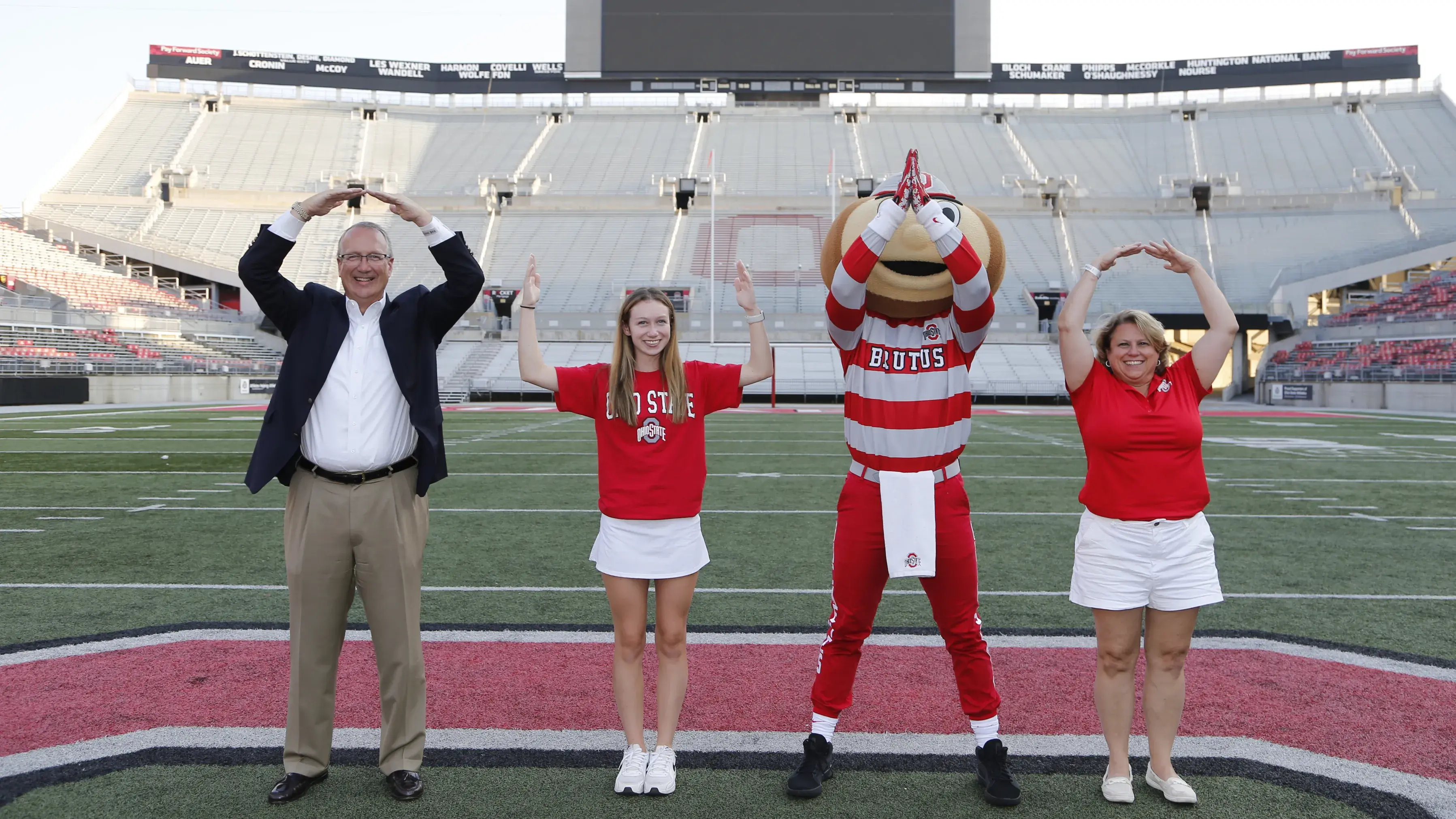 Student and parents recreate O H I O with brutus buckeye on the football field