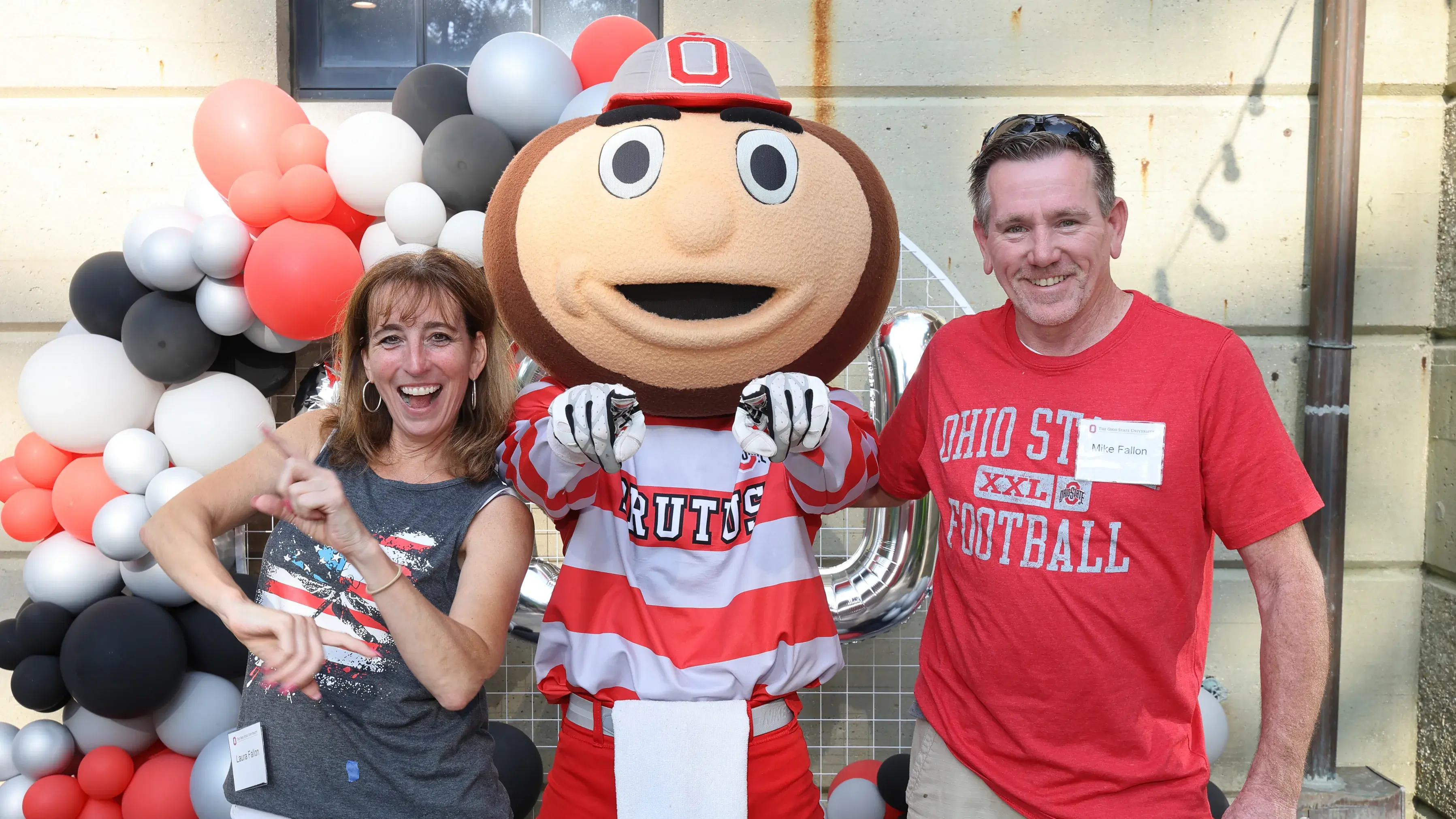 man and woman in ohio state t shirts pose for a picture with brutus buckeye