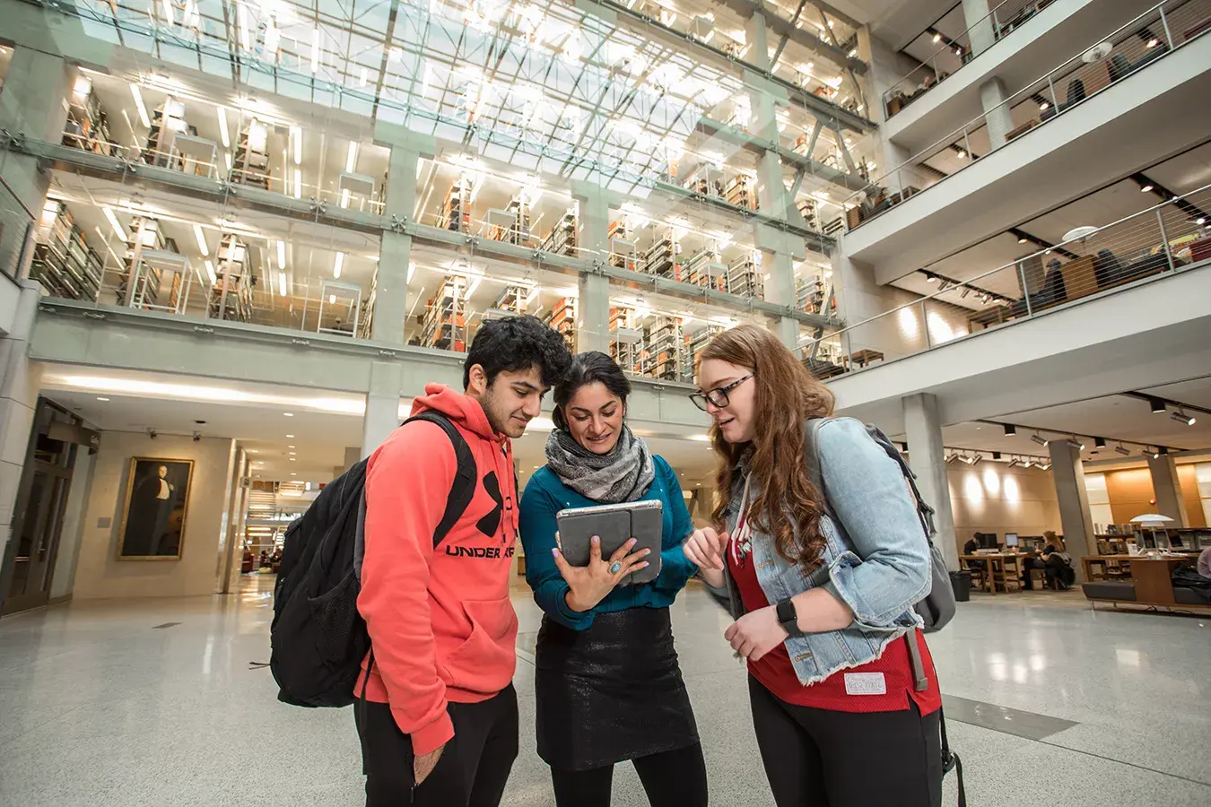 3 students looking at an ipad standing in front of a library on osu's campus