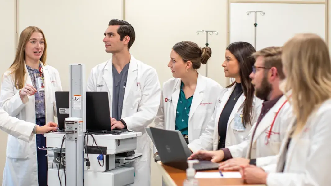 pharmacy students in a lab setting watching a man work on the computer