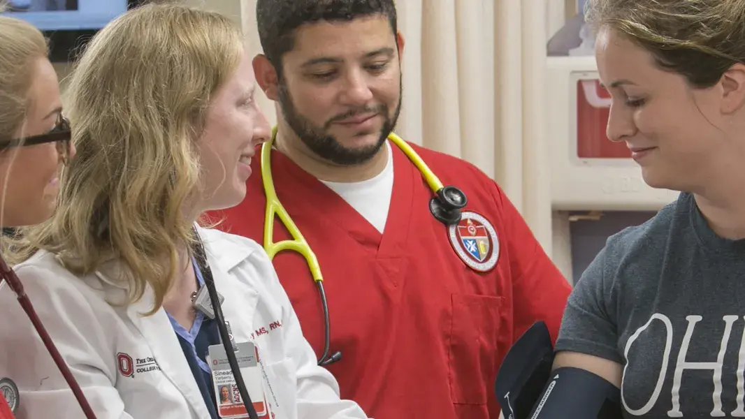 nursing students in red scrubs with stethoscopes talking