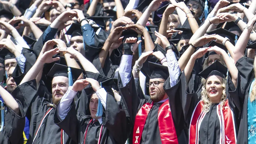 Ohio State students form O H I O in graduation caps and gowns