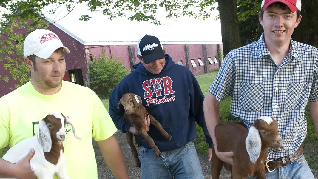 agriculture students holding small goats at a farm