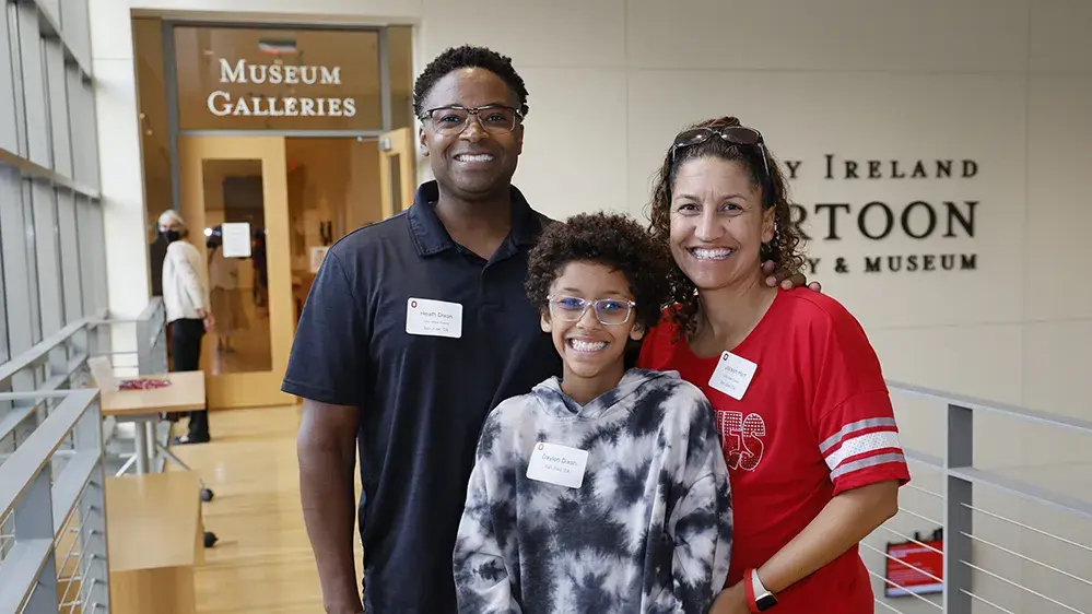 mother and father smiling proudly behind their OSU student daughter