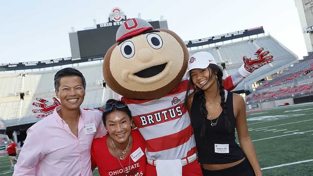 Family standing with Brutus Buckeye on field before a football game
