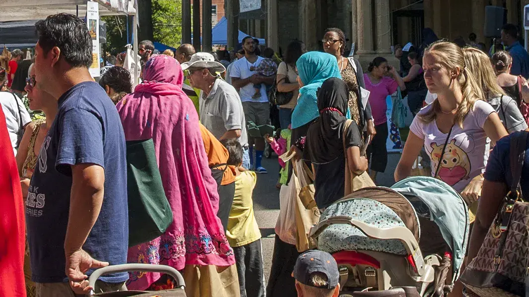 crowds of people wearing bright colored clothing walking on a street