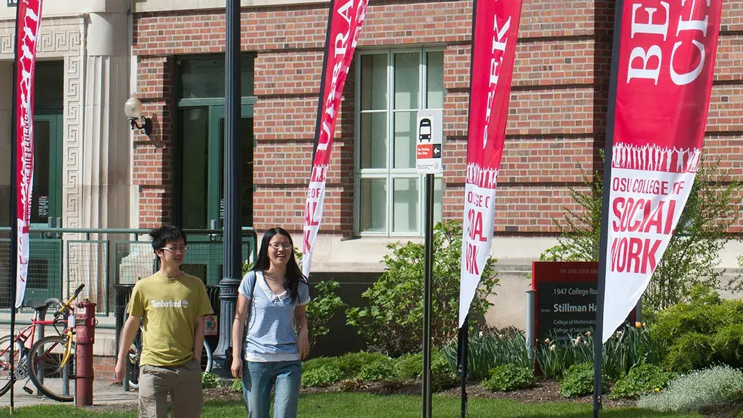 two students walking by banners in front of the college of social work