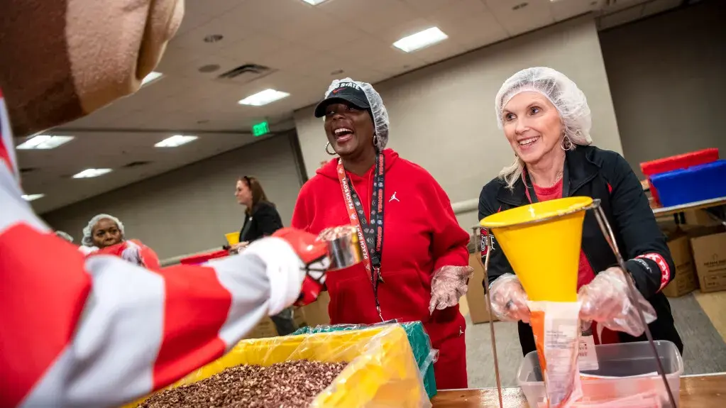 Melissa Shivers and Tracy Stuck packing food for the volunteer service project, Feed the Funnel 