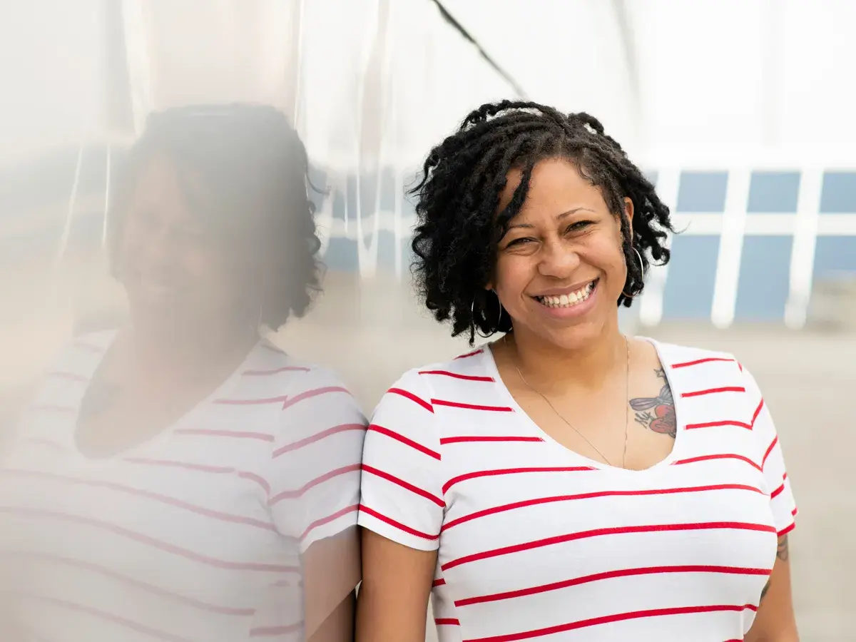 A woman leans against a reflective wall