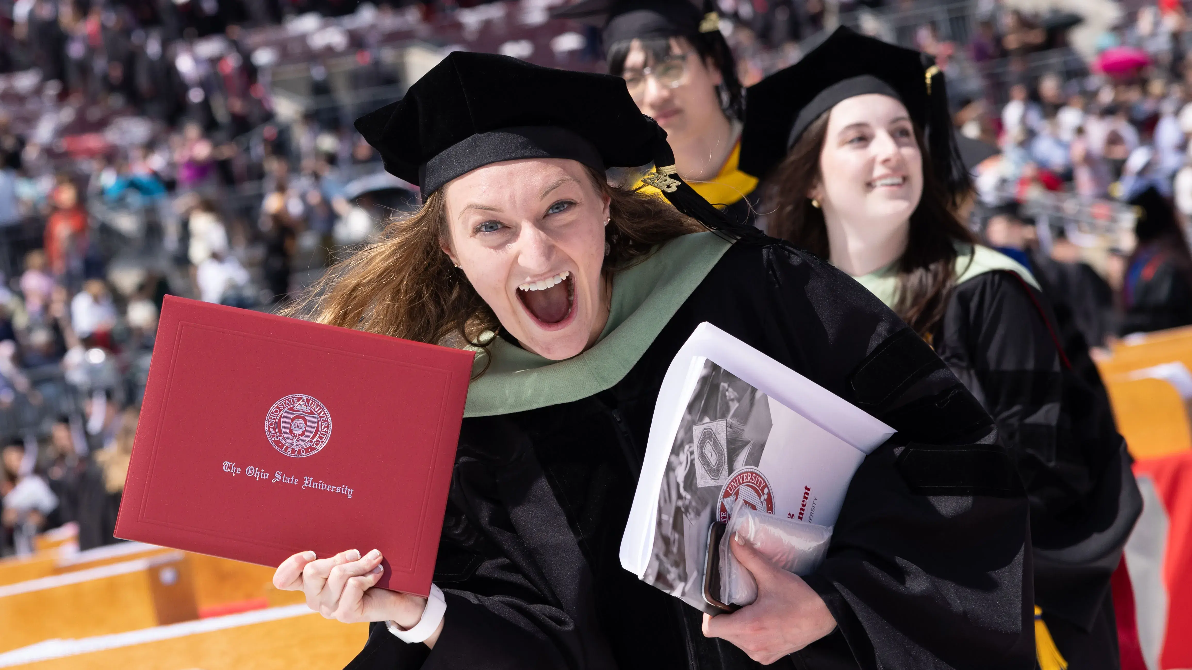 Excited students walking in their graduation ceremony with diplomas in hand