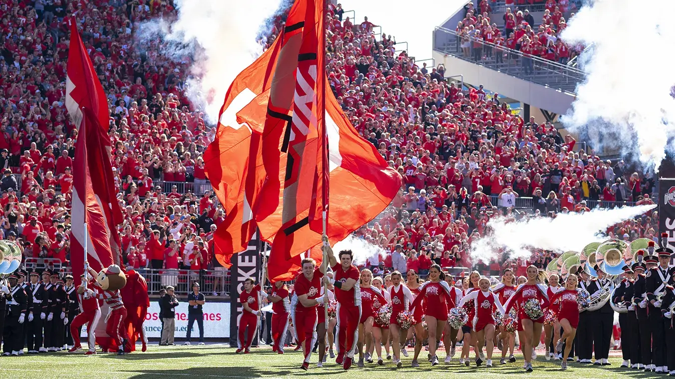 Ohio State Cheerleaders carrying oversized flags onto the field 